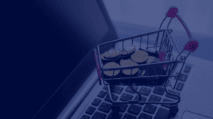 A miniature shopping cart filled with gold coins sits on a laptop keyboard in this close-up studio shot. The composition highlights the concept of online spending, digital transactions, and the ease of ecommerce. The muted lighting and modern laptop design creates a sophisticated feel, making this image ideal for conveying themes of financial technology, investments, digital marketing, and online commerce.