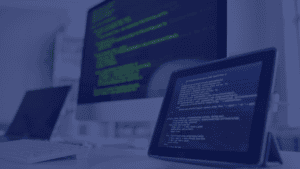 This photo showcases a brightly lit office setting, dominated by a computer and tablet displaying lines of code. A partially visible laptop and keyboard suggest a workspace focused on technology. The setup, against a blurred backdrop, evokes a modern and professional atmosphere. This image is ideal for projects centered on programming, software development, or digital workspaces, embodying themes of innovation, precision, and technological advancement.