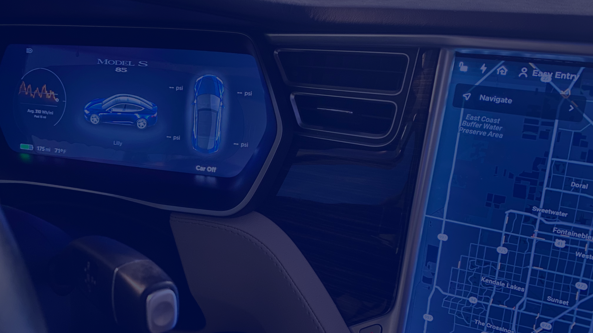 A close-up shot shows the interior of a car, featuring two illuminated screens. The left screen displays a graphic of a blue car along with some metrics. The screen on the right shows a navigation map. The interior is sleek with an aesthetic finish. This photograph could be used for projects about travel and technology, car interiors, navigation systems, and vehicle design.